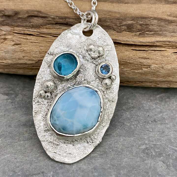 This is a picture of a silver pendant set with blue gemstones