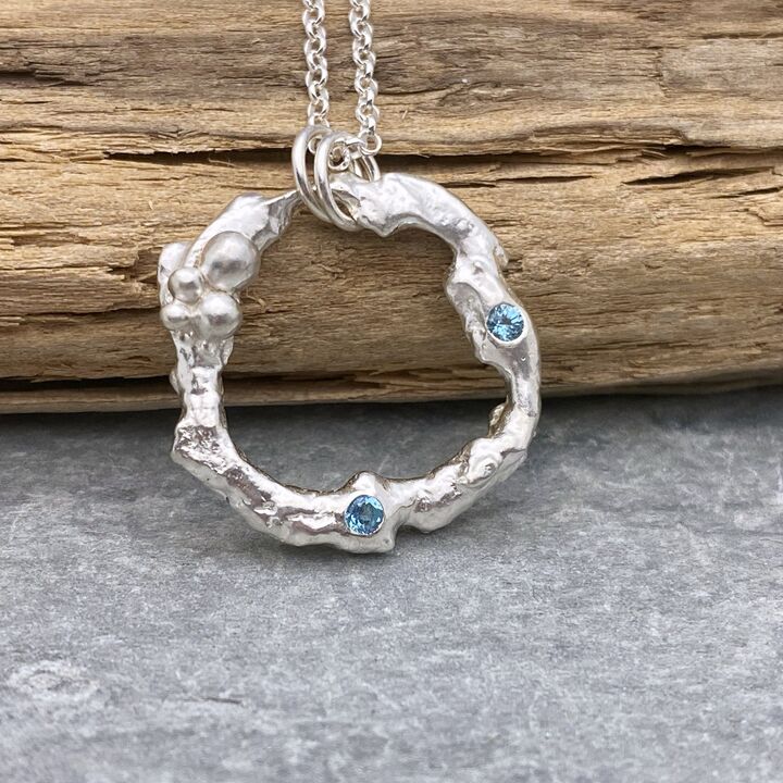 Organic silver circle pendant with two blue Topaz stones. 3