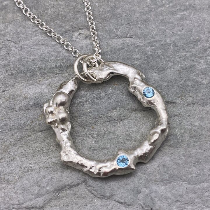 Organic silver circle pendant with two blue Topaz stones. 2