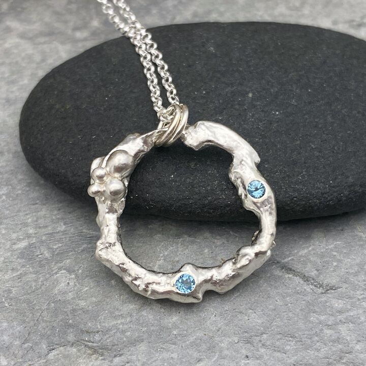 Organic silver circle pendant with two blue Topaz stones.